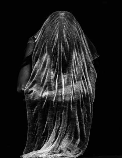 Silhouette humaine recouverte d’un voile, photographie artistique en noir et blanc.