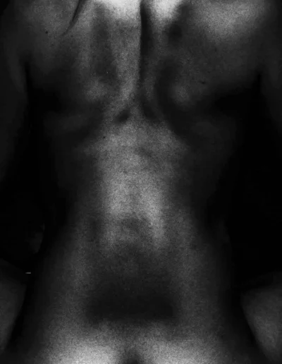 Dos nu en clair-obscur, photographie en noir et blanc au grain marqué.